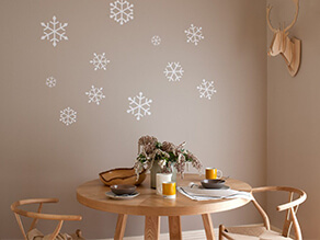 Soft neutral dining setting with painted snowflakes and timber table and chairs and deer head art